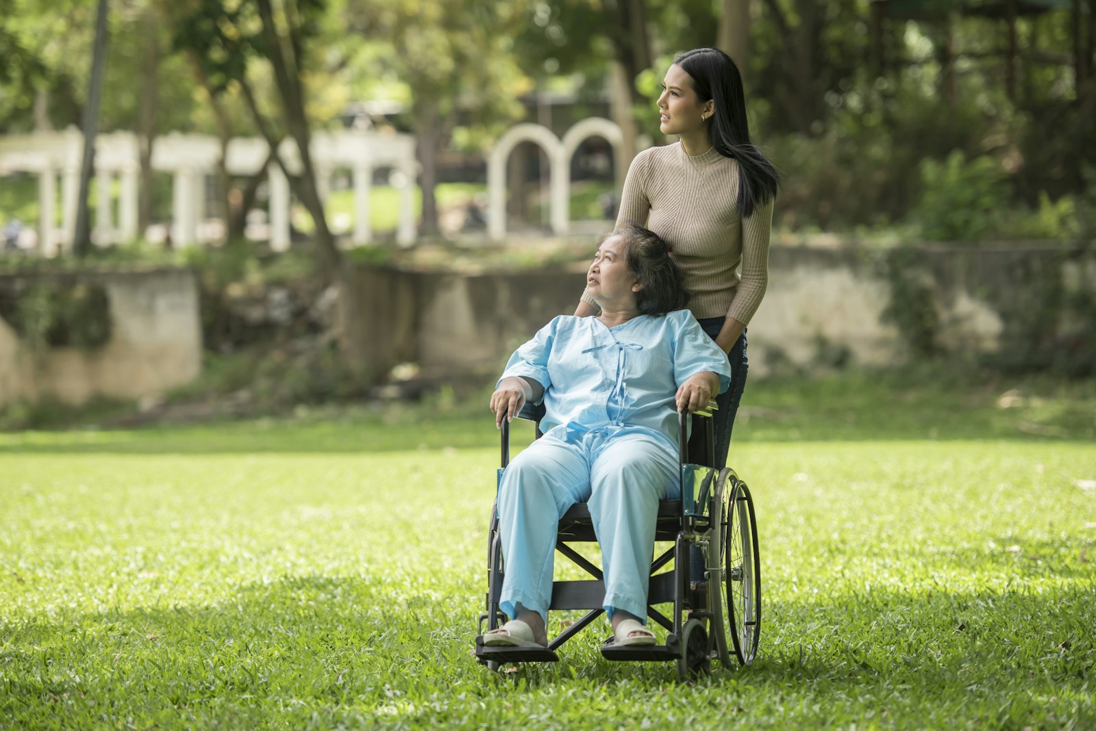 Support worker with a man in a wheelchair in a park